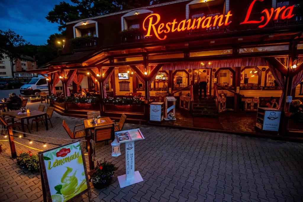 a restaurant with tables and a sign in front of it at Pensiune Restaurant Lyra in Corunca