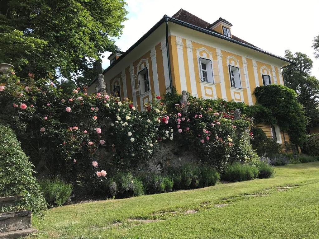 a yellow house with pink roses in front of it at Sattelzimmer und Studio in Pischeldorf