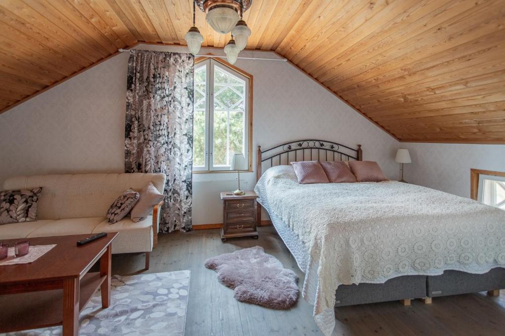 a bedroom with a bed and a couch and a window at Saaristohotelli Vaihela in Velkua