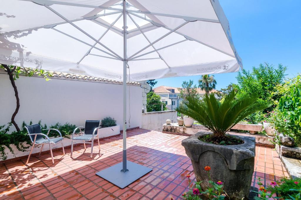 a white umbrella on a patio with chairs and a plant at Apartments Paula in Dubrovnik