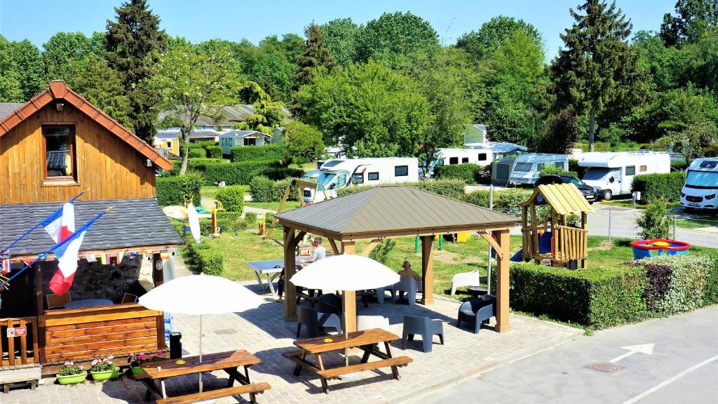 Camping Paris Beau Village في Villiers-sur-Orge: مجموعة من طاولات التنزه والمظلات في الحديقة