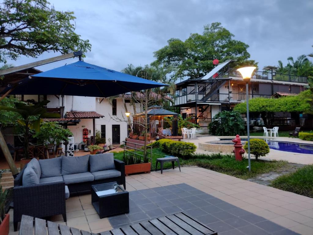 a patio with a couch and an umbrella and a building at Villa Juana Hotel in Pereira