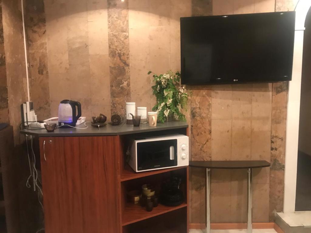 a microwave on a stand with a tv on a wall at DESYATINNAYA Hostel in Kyiv