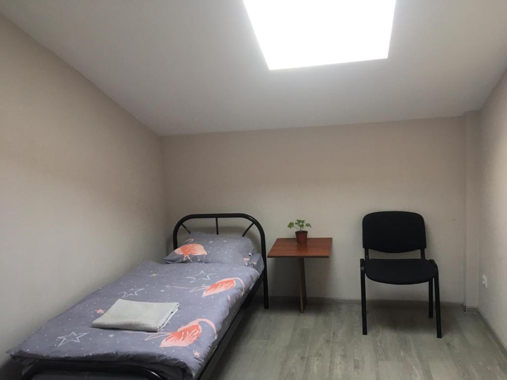 a small bedroom with a bed and a chair at Gelena in Uzhhorod