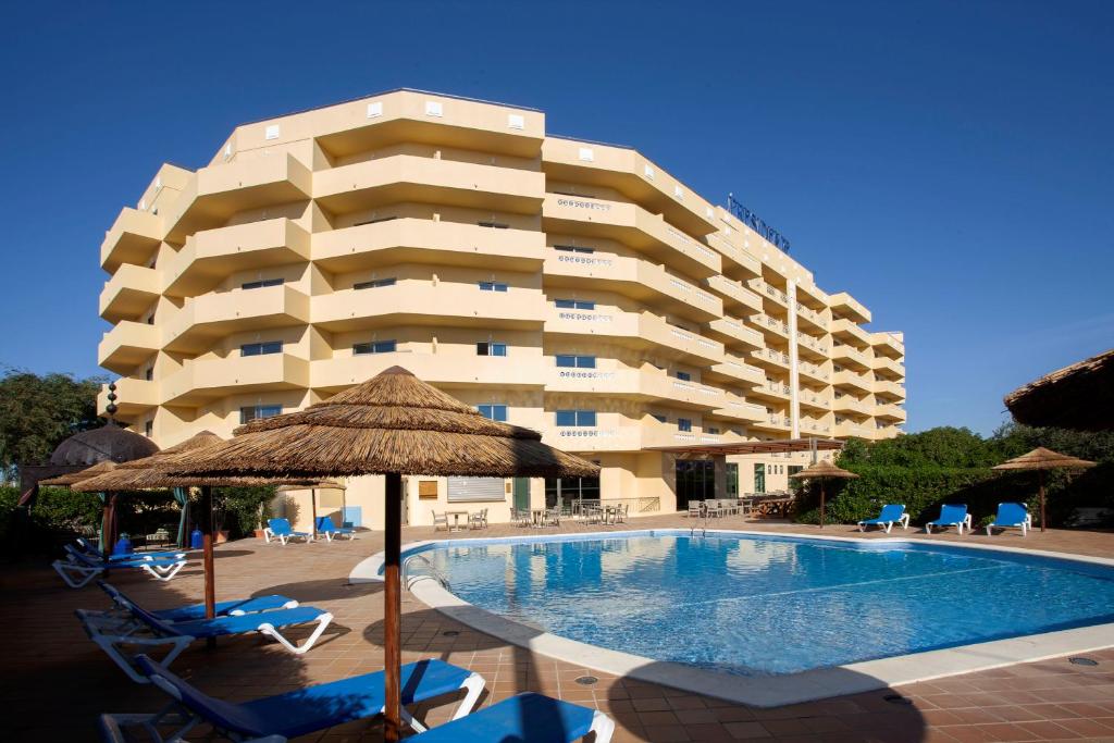 een hotel met een zwembad en stoelen en een gebouw bij TURIM Presidente Hotel in Portimão