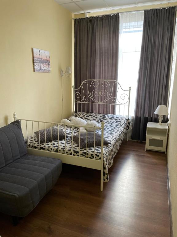 a bedroom with a bed and a couch and a window at Hostel Milan in Moscow