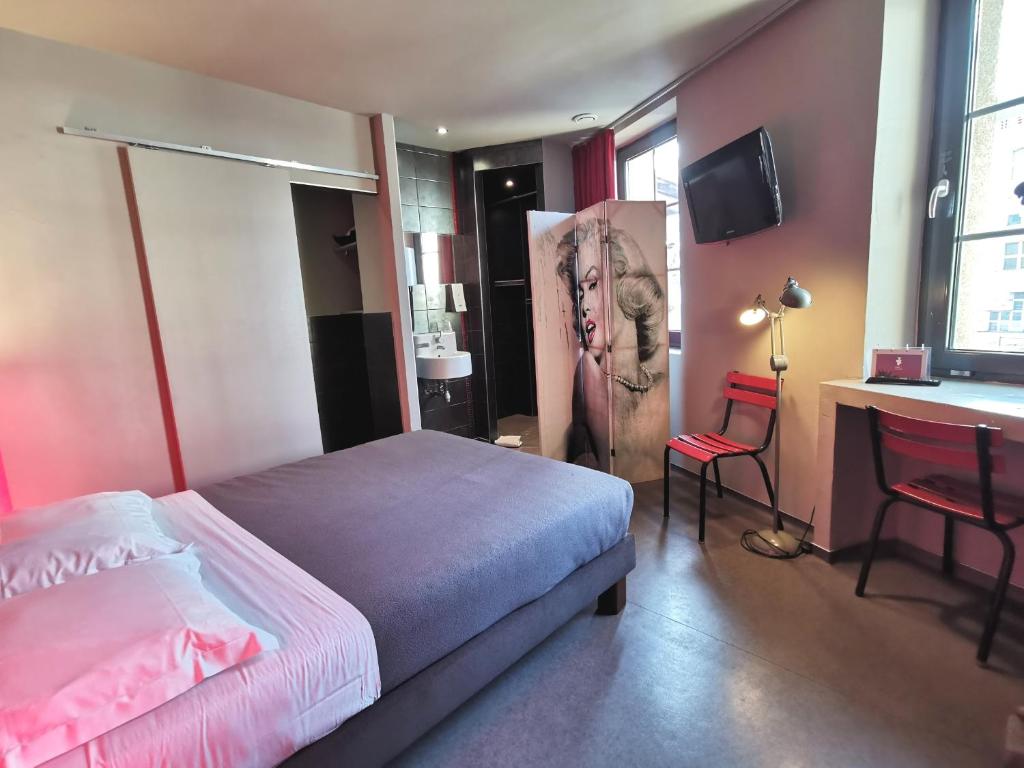 a bedroom with a bed and a desk and a television at 7Art Hotel in Cannes