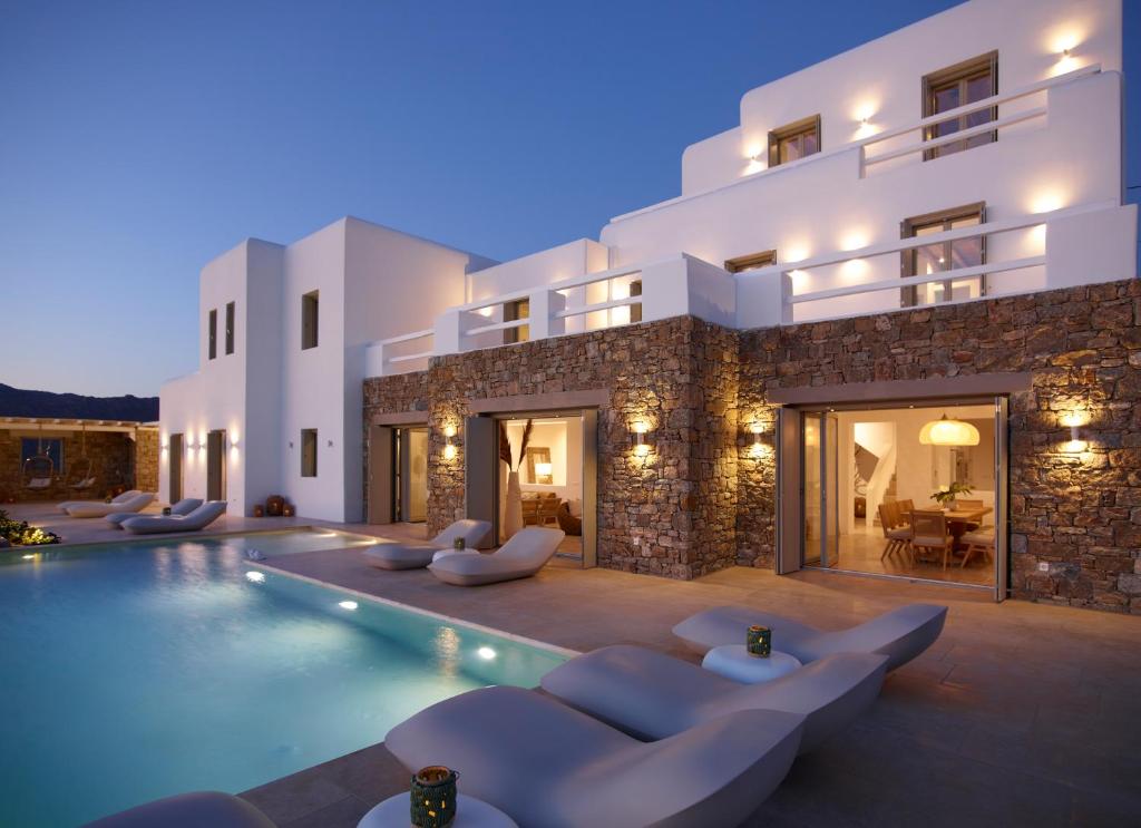 a villa with a swimming pool in front of a building at Absolute Paradise Villa Tourlos in Mikonos