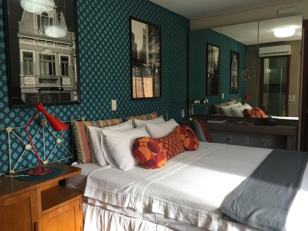 a bedroom with a large bed and a mirror at Porto Retrô Residence in Porto Alegre