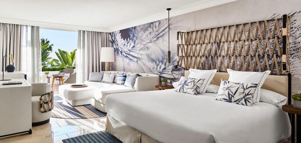 a bedroom with a large white bed and a couch at Puente Romano Marbella in Marbella