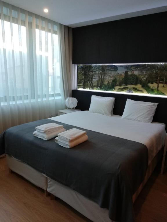 1 dormitorio con 1 cama grande y 2 toallas. en NEW!! Galé 404 Center Apartment (wifi, parking...) en Oporto