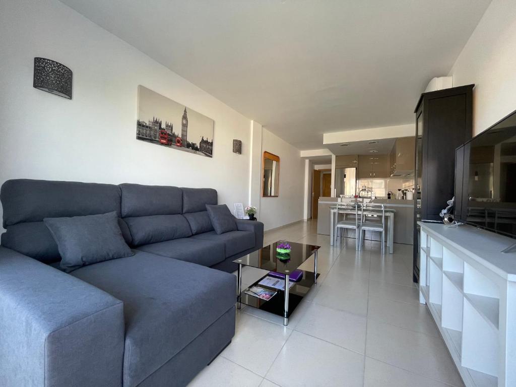 a living room with a blue couch and a kitchen at Samsara Beach in Port d'Alcudia