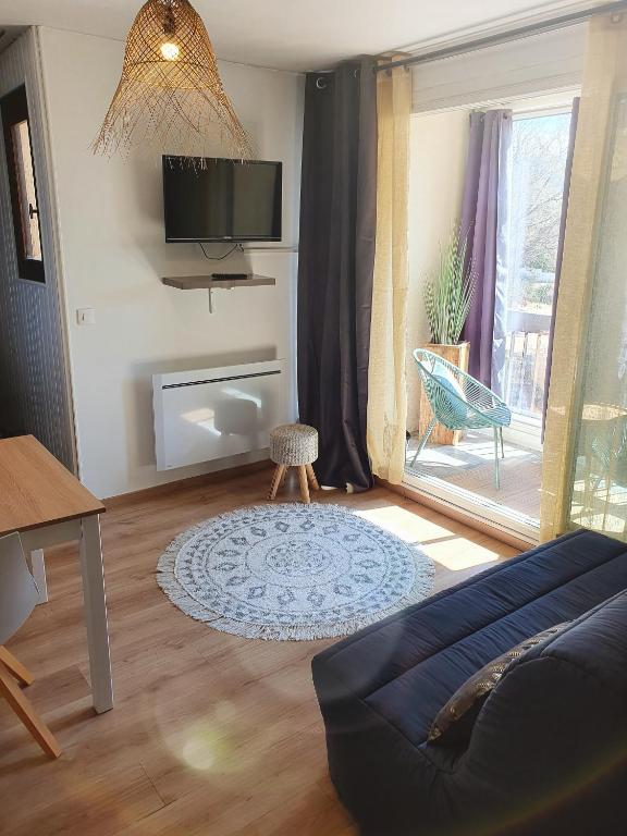 un salon avec un canapé et une télévision au mur dans l'établissement Le bohème chic !, à Gréoux-les-Bains