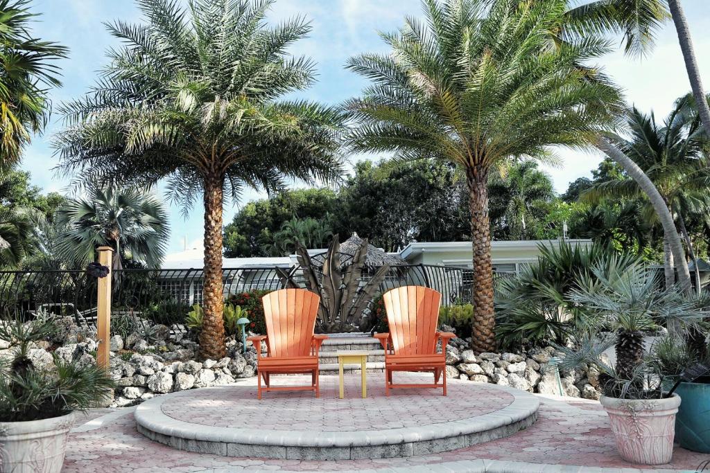 due sedie e un tavolo in un giardino con palme di Kona Kai Resort and Gallery a Key Largo