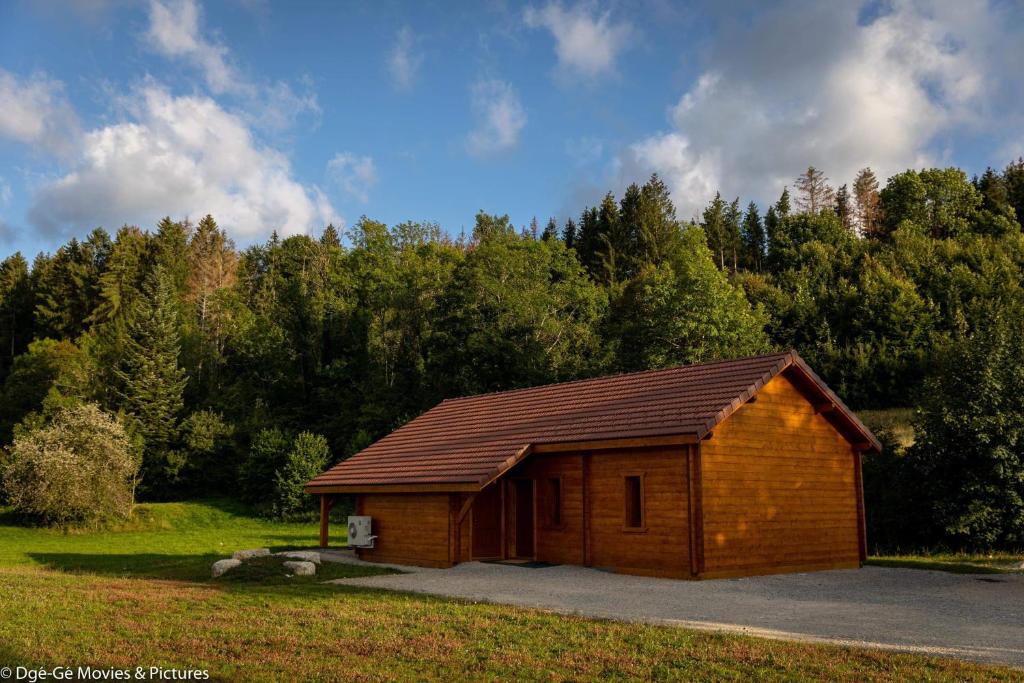 un pequeño edificio de madera en un campo con árboles en Les Jardins du Hérisson Chalet 1, en Bonlieu