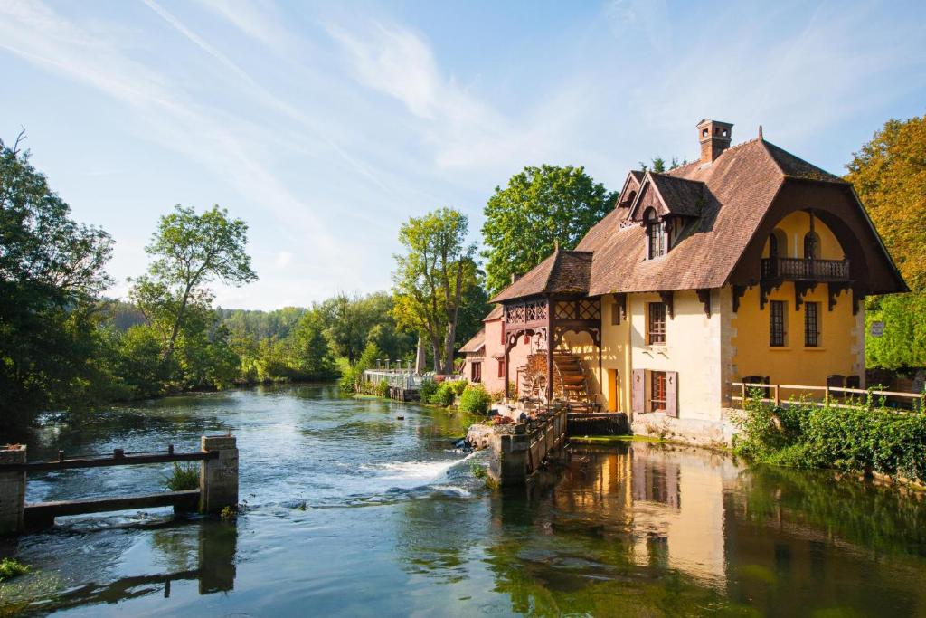 een huis aan een rivier naast een gebouw bij Moulin de Fourges in Fourges