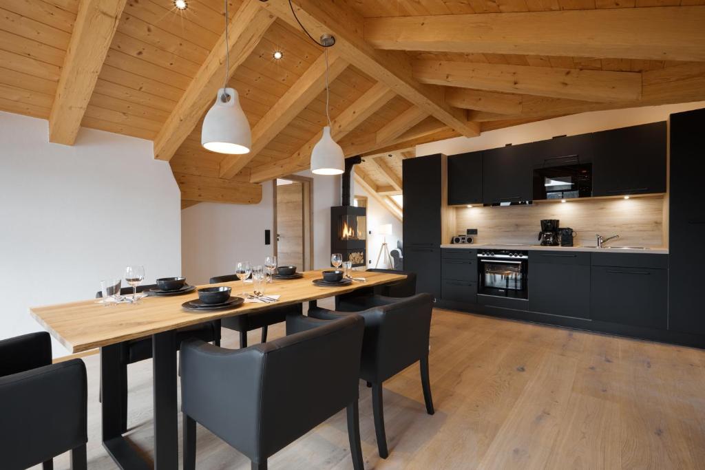 a dining room with a wooden table and black chairs at Zugspitzerei - Premium Chalet Ferienwohnungen in Grainau