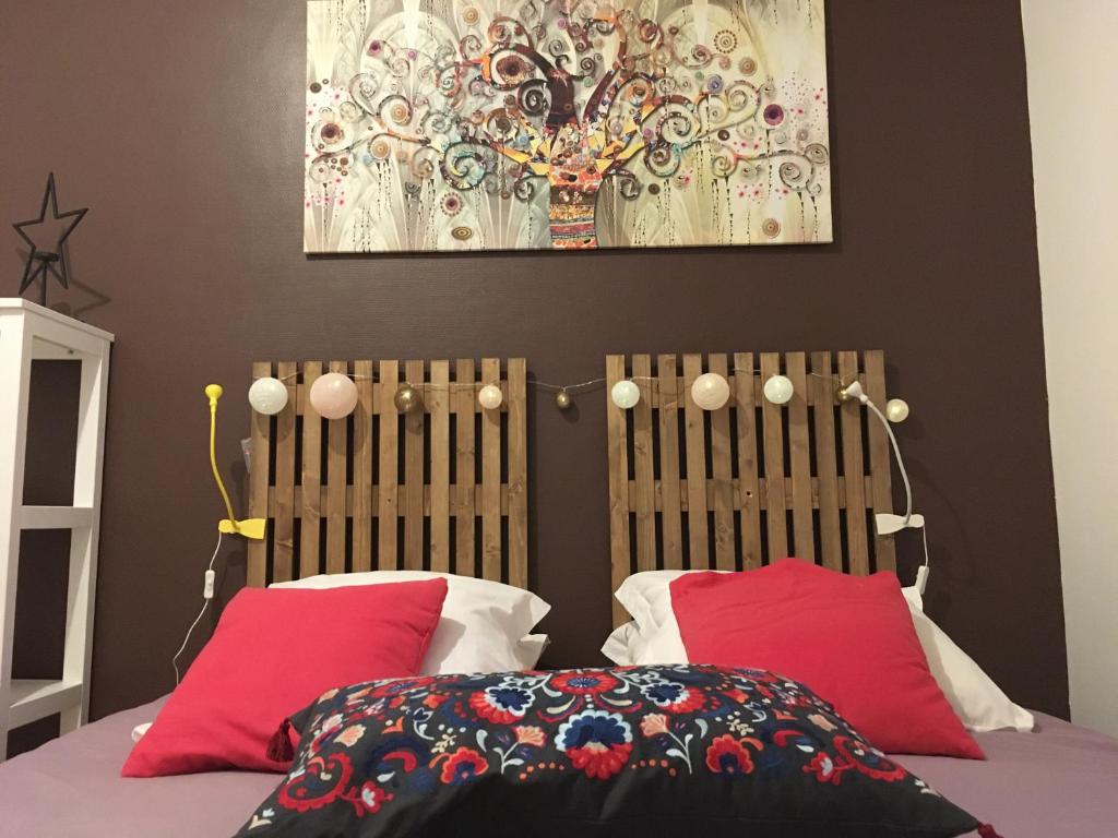 ein Schlafzimmer mit einem Bett mit roten Kissen und einem Gemälde in der Unterkunft L auberge du lion d or in Nanteuil-sur-Marne