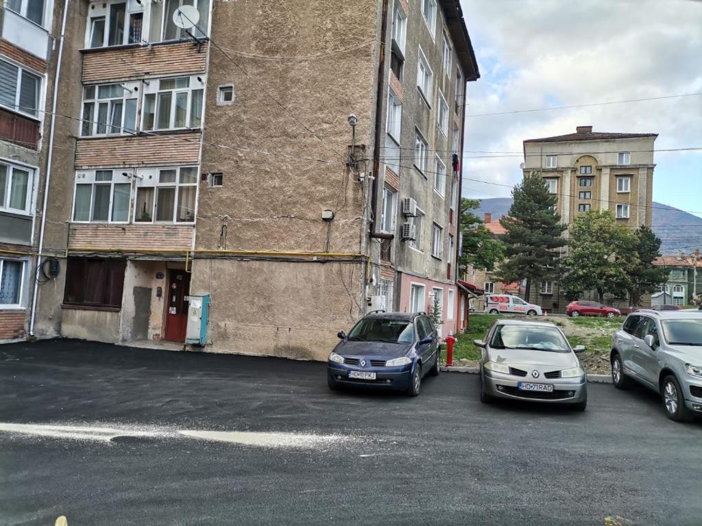 drie auto's geparkeerd op een parkeerplaats naast een gebouw bij Sophia Lupeni Straja in Lupeni