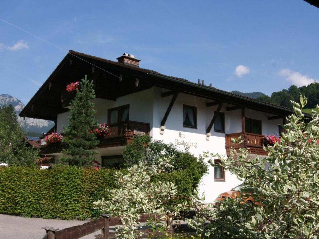 a white house with a black roof and flowers at Haus am Reschenberg Ferienwohnungen in Ramsau