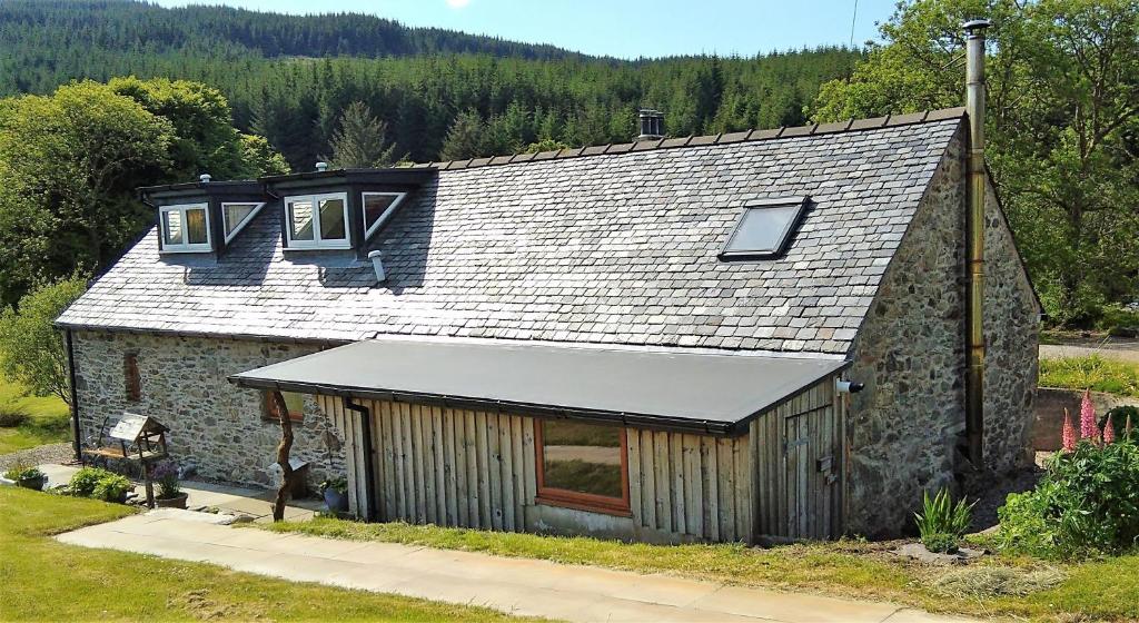 a stone house with a gray roof and windows at Auchnabreac Cottage in Carradale