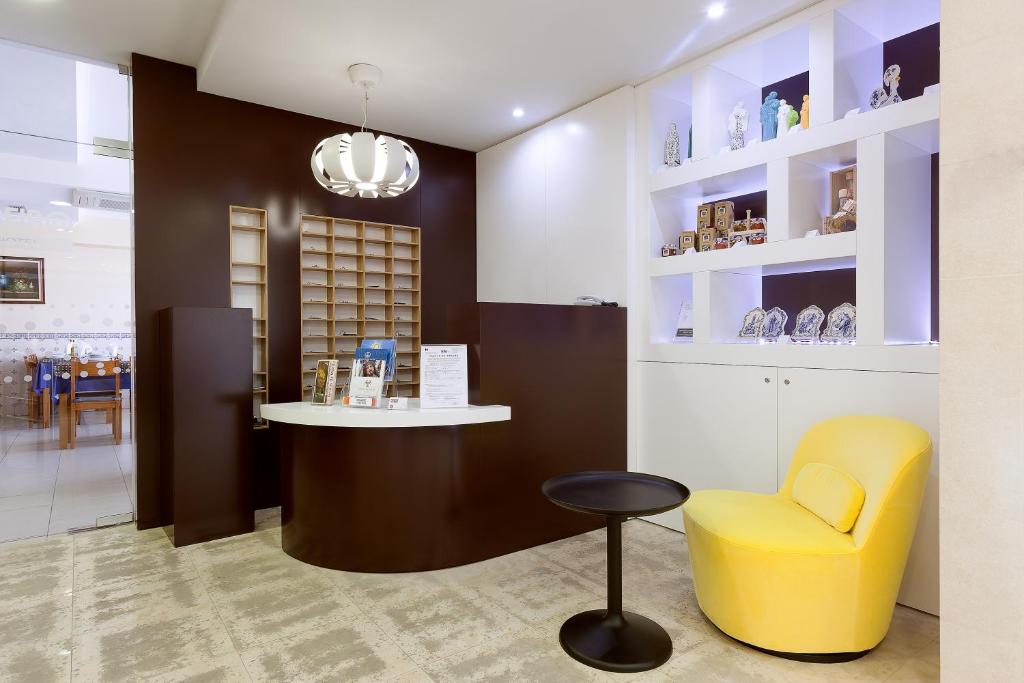 un salon avec une chaise jaune et un comptoir dans l'établissement Ribeiro Hotel, à Fátima