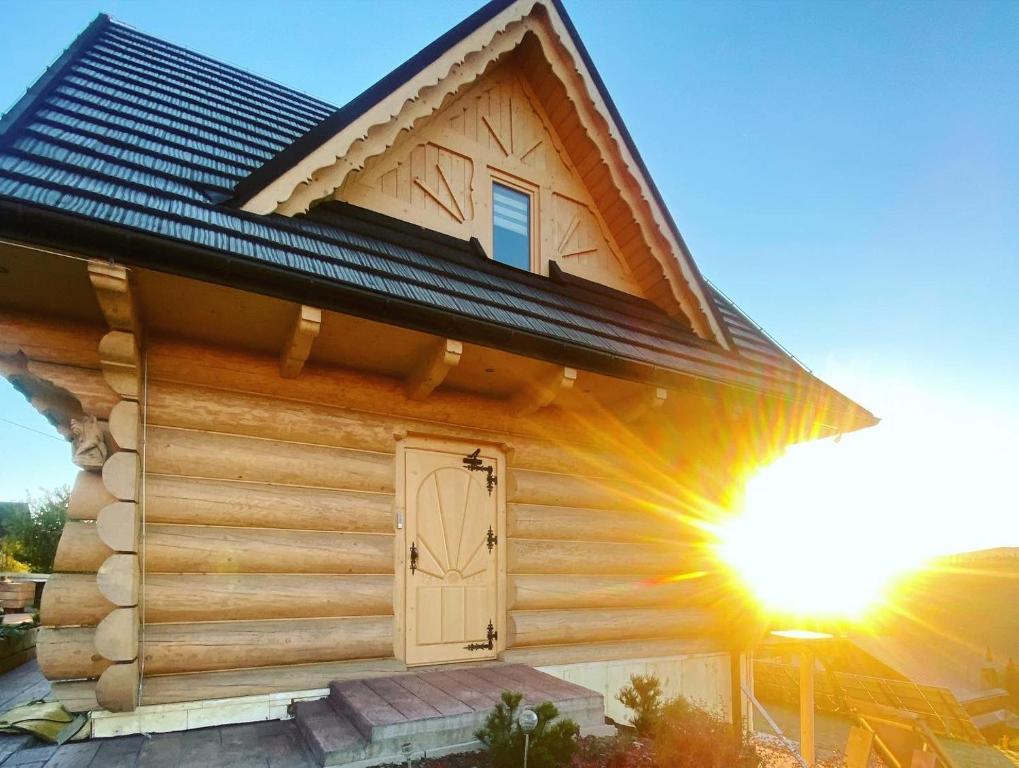 a log cabin with a door and the sun shining at Domki Góralskie Dwa Misie in Bukowina Tatrzańska