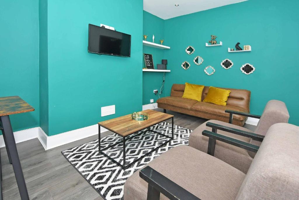a living room with a couch and a tv on a blue wall at Townhouse @ 202 Walthall Street Crewe in Crewe
