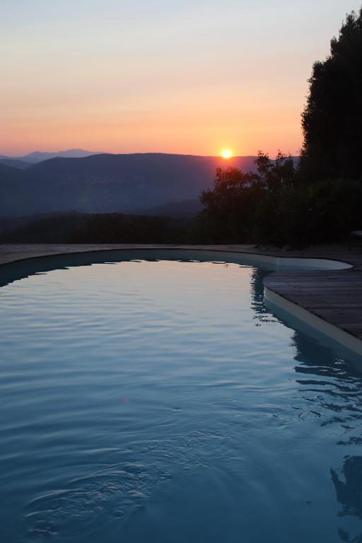 a swimming pool with a sunset in the background at La Vela in Peille