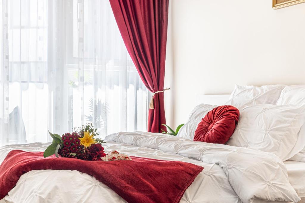 een wit bed met een rode deken en bloemen erop bij ARI RED Apartment în complexul Ared Kaufland in Arad