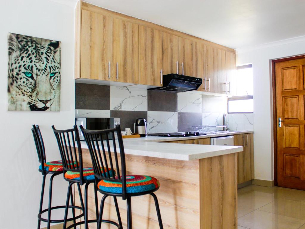 a kitchen with a counter and three bar chairs at Proleefic House on Florence in Bellville