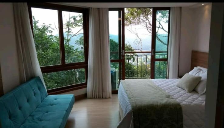 a bedroom with a bed and a couch and large windows at Flat Vista Azul Hotel in Pedra Azul