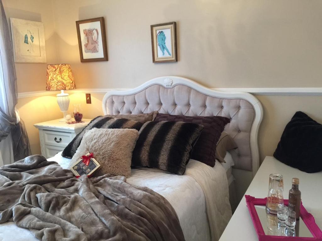 una camera da letto con un grande letto bianco con cuscini di FLAT DE CHARME RÚSTICO EM GRAMADO a Gramado