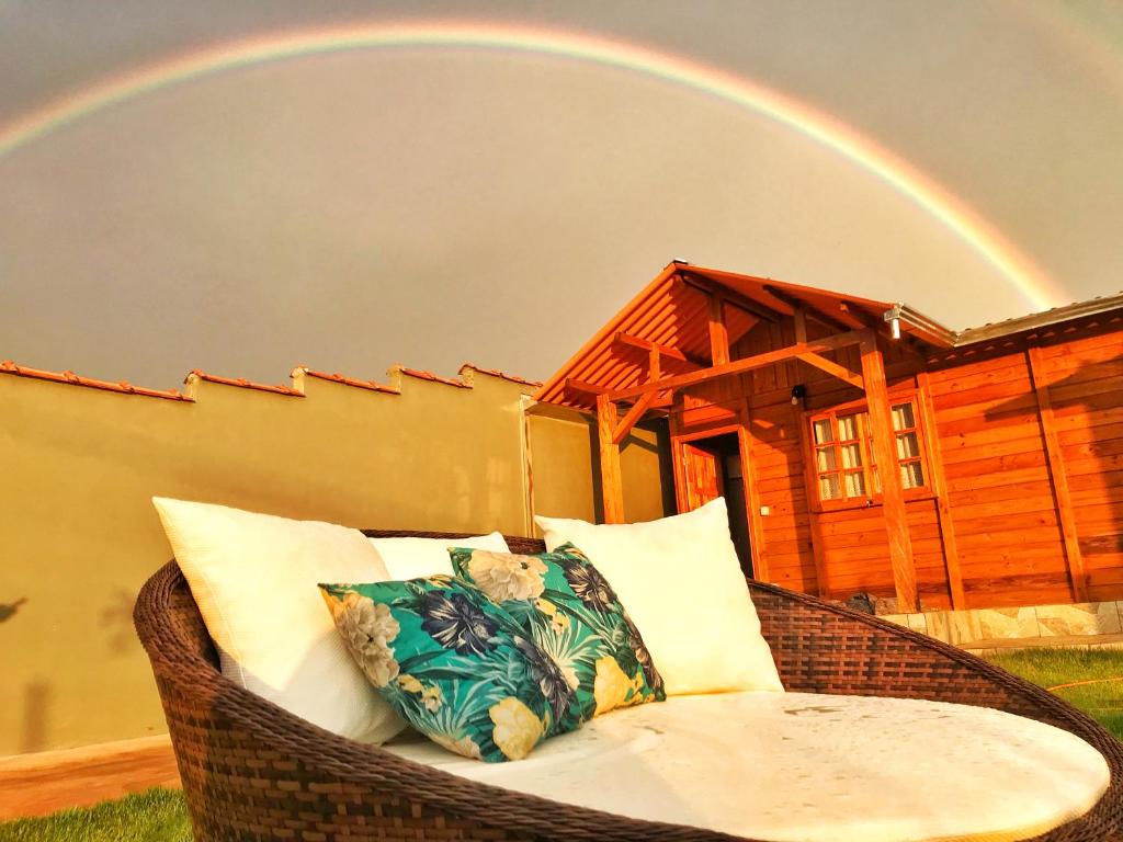 uma cadeira de vime com um arco-íris ao fundo em Casa de Madeira em Delfinópolis