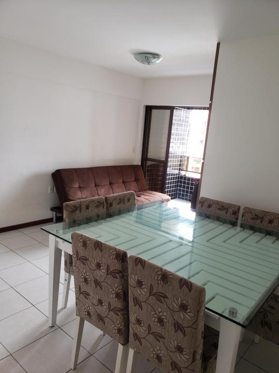a dining room with a glass table and a couch at Apt 2 quartos acomoda 10 pessoas a 450 metros da praia de Jatiúca in Maceió