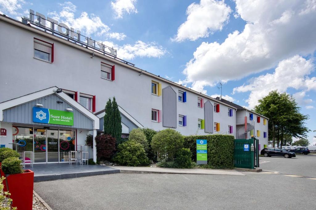 un bâtiment blanc avec des fenêtres colorées dans un parking dans l'établissement Sure Hotel by Best Western Nantes Saint-Herblain, à Saint-Herblain