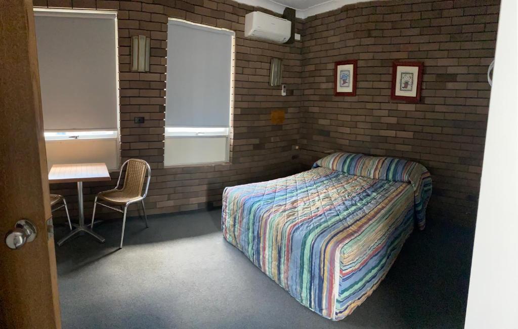 a bedroom with a bed and a table and a desk at Downtown Motel in Wollongong