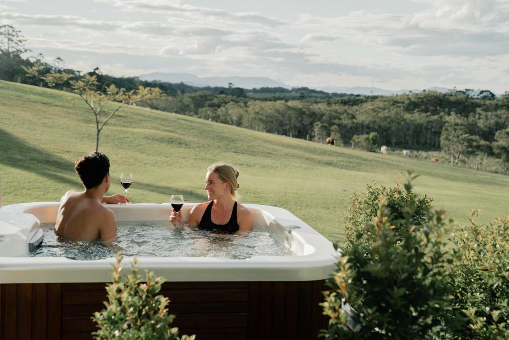 a man and a woman in a bath tub with wine at Cape Byron Retreat (Adults-Only) in Byron Bay