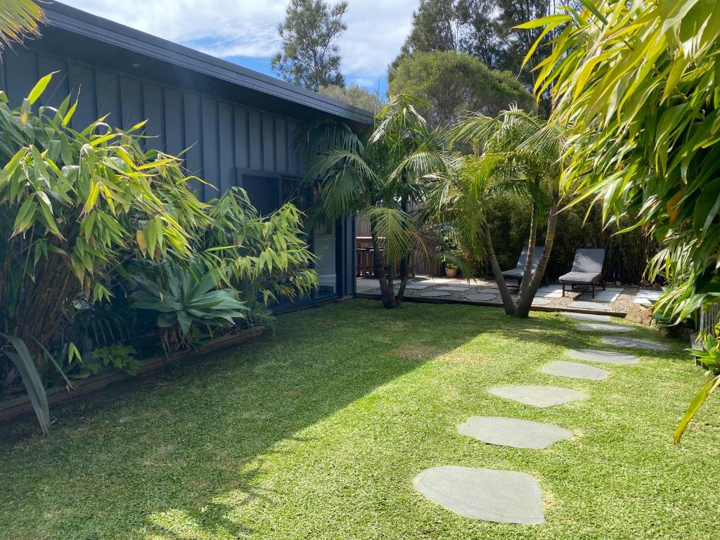 a garden with grass and rocks in front of a house at Bali In Berrara in Berrara