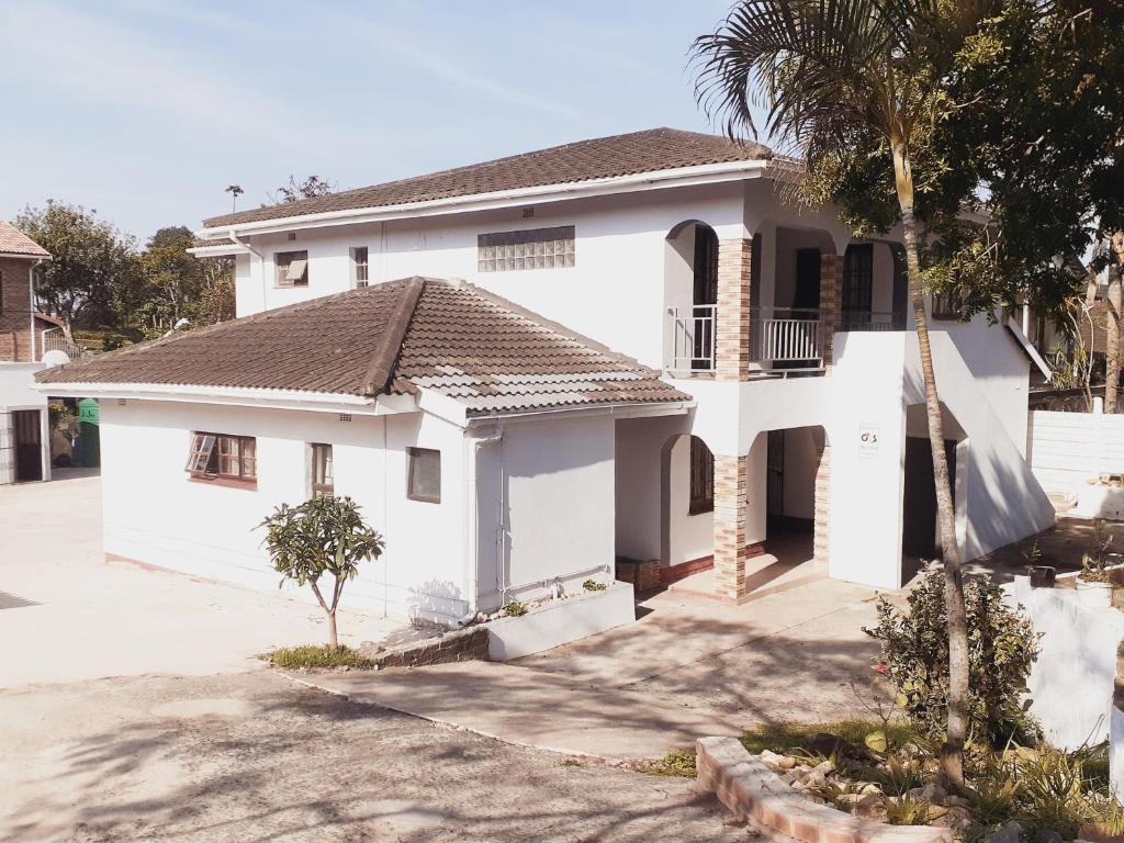 a white house with a palm tree in front of it at Gabade Guest House in KwaDukuza