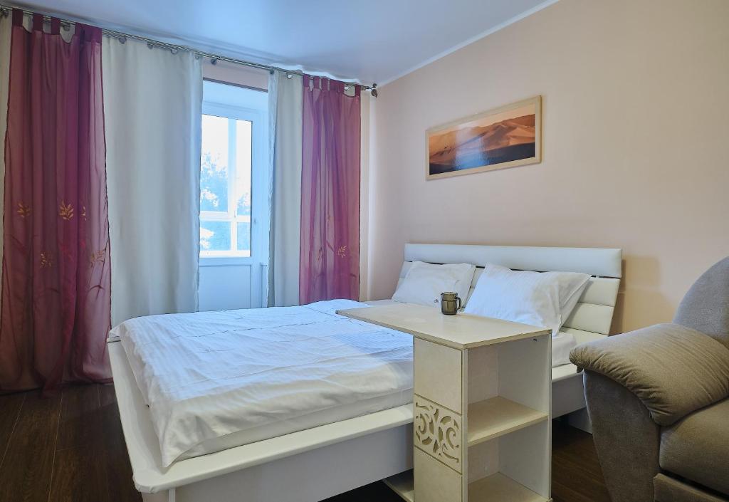 a small bedroom with a bed and a chair at Apart Petrovskie on Sovetskaya 69 in Tomsk