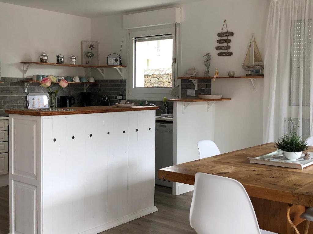 a kitchen with a wooden table and white cabinets at Bel appartement en rez-de-jardin à 100m des plages in Saint-Nazaire
