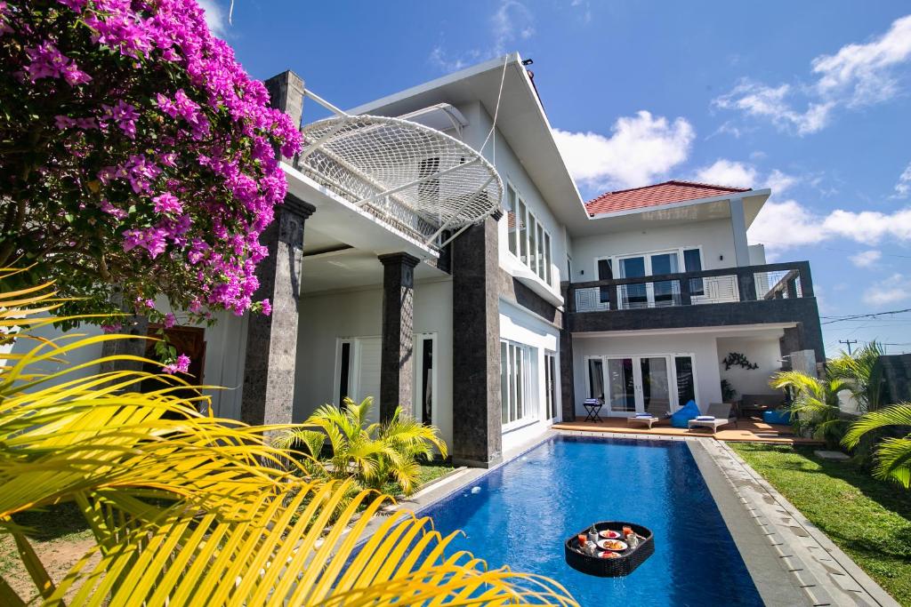 a villa with a swimming pool in front of a house at Villa Haka Jimbaran by Nagisa Bali in Jimbaran