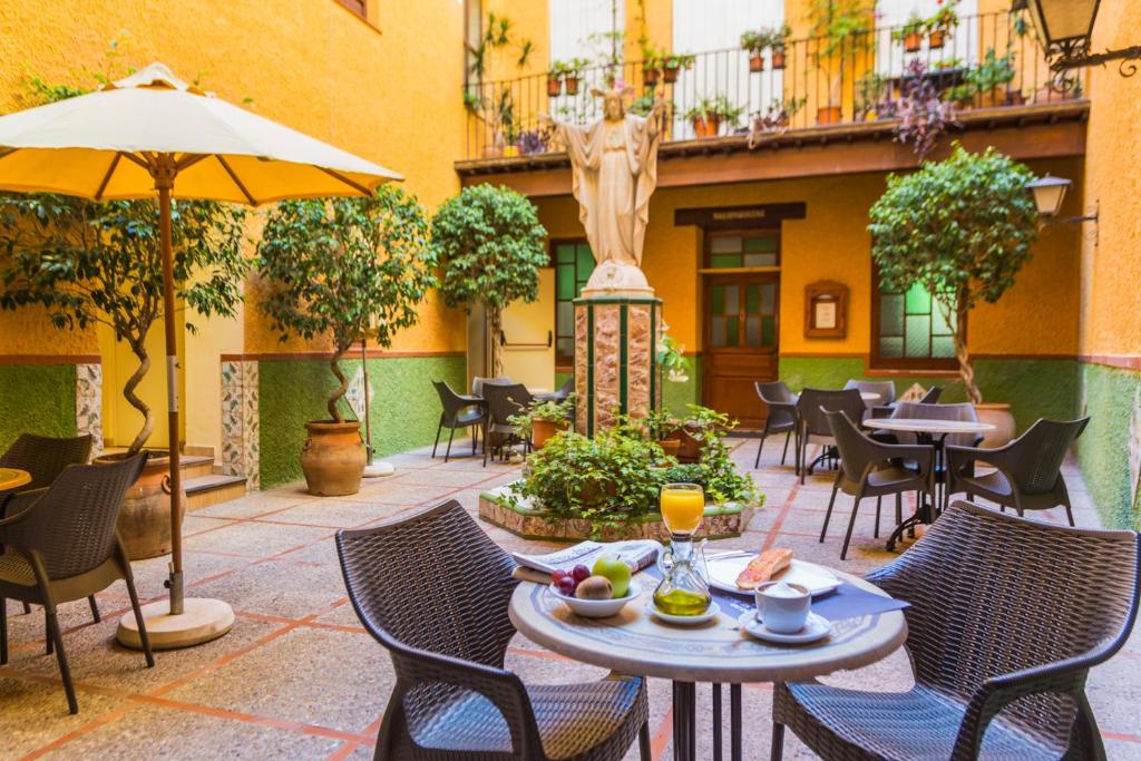 eine Außenterrasse mit Tischen, Stühlen und einem Sonnenschirm in der Unterkunft Hostal Loreto in Denia