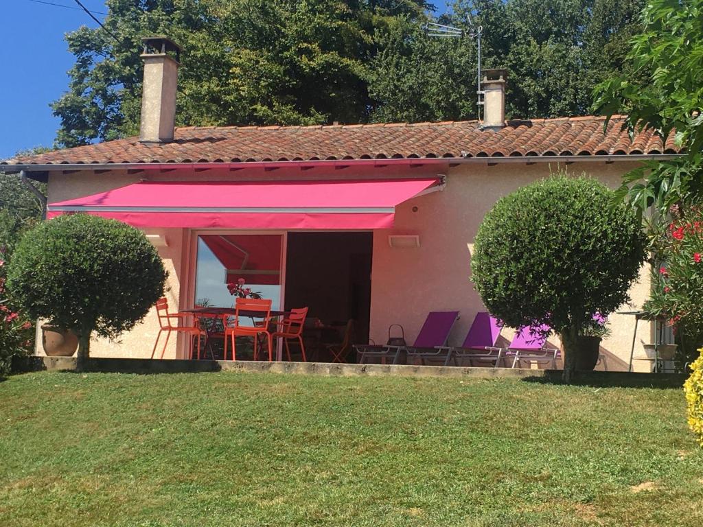 una casa con toldo rosa y sillas en un patio en Gite Au Bouzigues, en Monlaur-Bernet