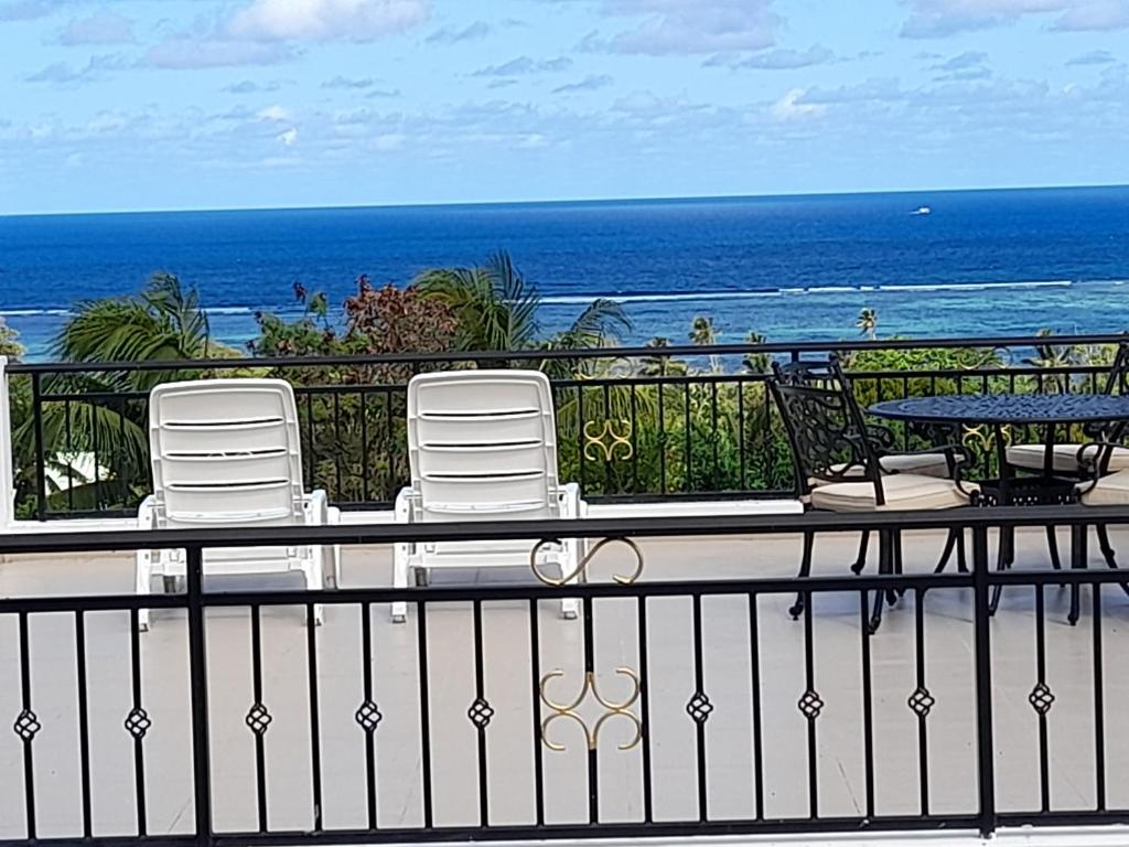 a balcony with chairs and a table and the ocean at Dawn Self-Catering in Anse aux Pins