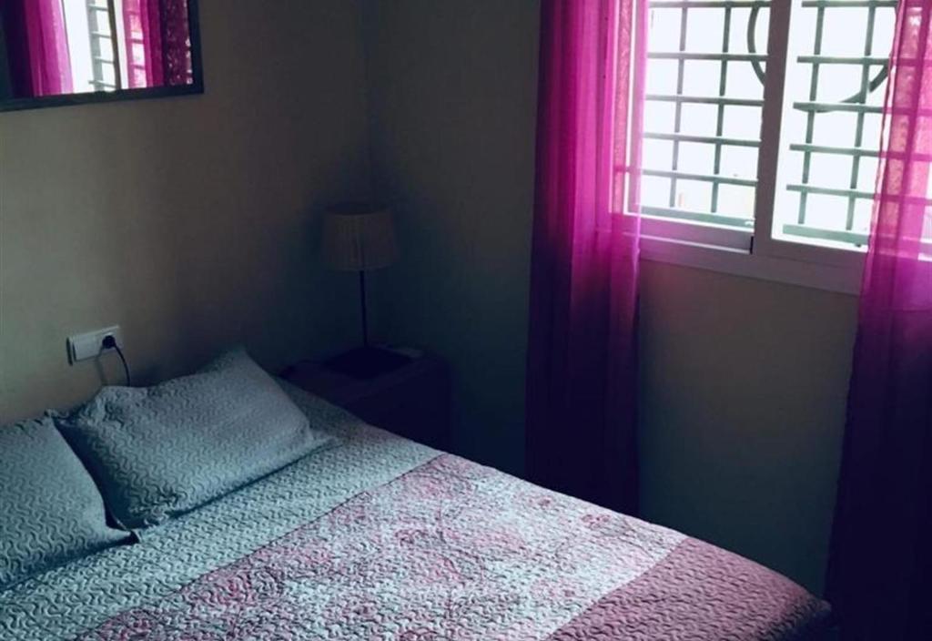 sypialnia z łóżkiem i oknem z różowymi zasłonami w obiekcie Lux Apartm Beauvivir w mieście Torre del Mar