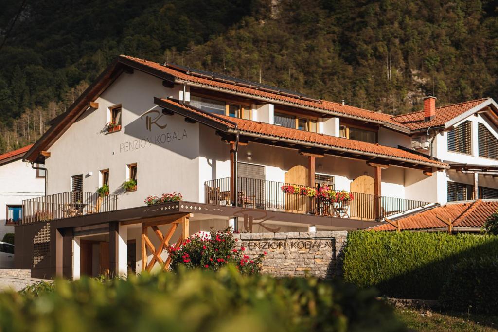 - un grand bâtiment blanc avec des balcons et des fleurs dans l'établissement Hotel Penzion Kobala, à Tolmin