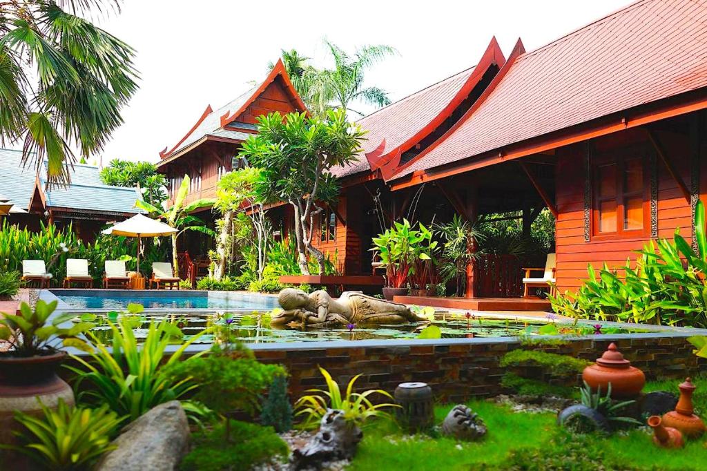 uma casa com piscina em frente a uma casa em Ruenkanok Thaihouse Resort em Hua Hin