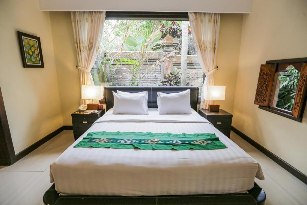sypialnia z dużym łóżkiem i oknem w obiekcie Ubud Hotel & Cottages w mieście Malang